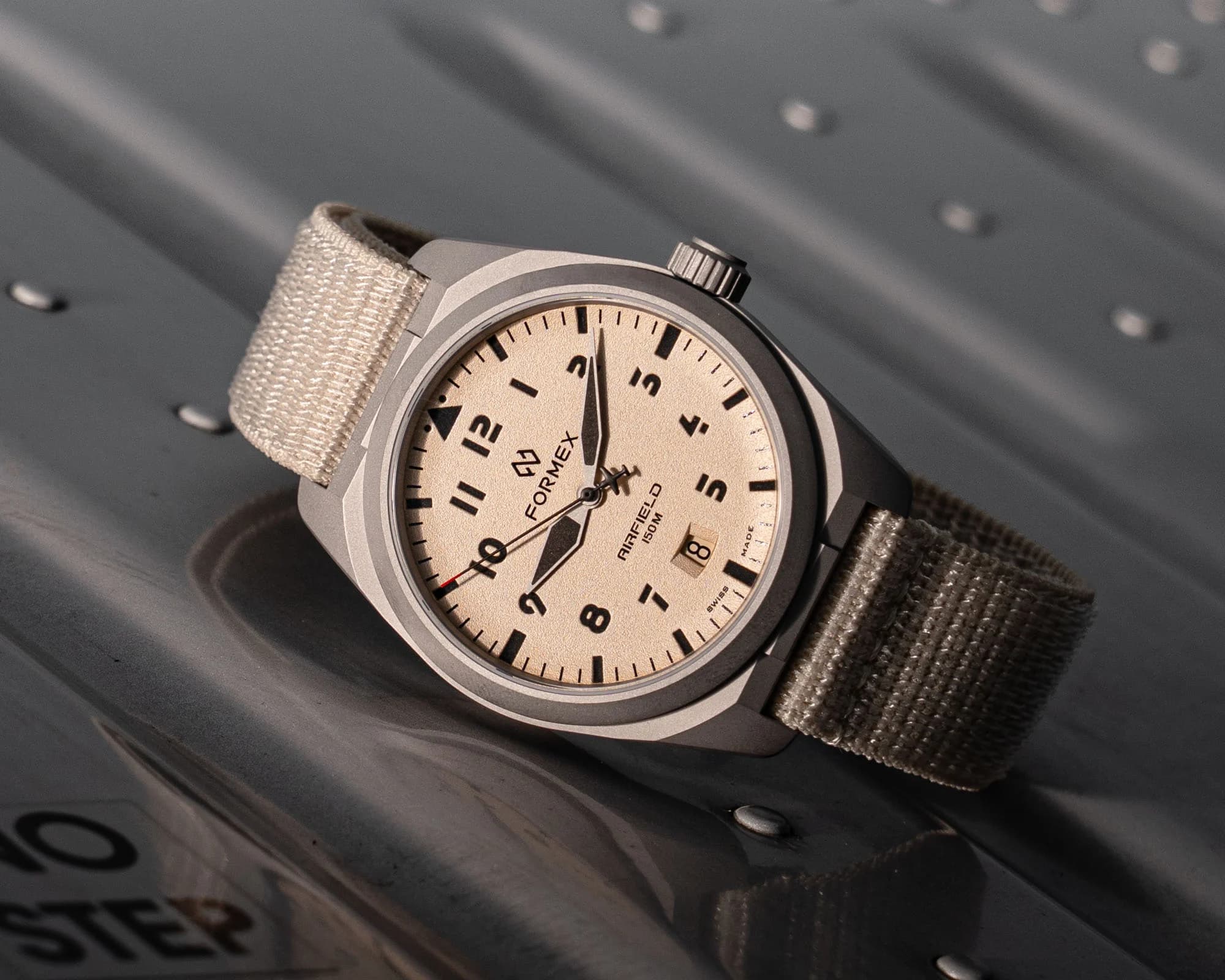 Formex AirField Automatic Desert Sand mit sandfarbenem Zifferblatt und hellem Textilband auf genieteter Flugzeugbeplankung