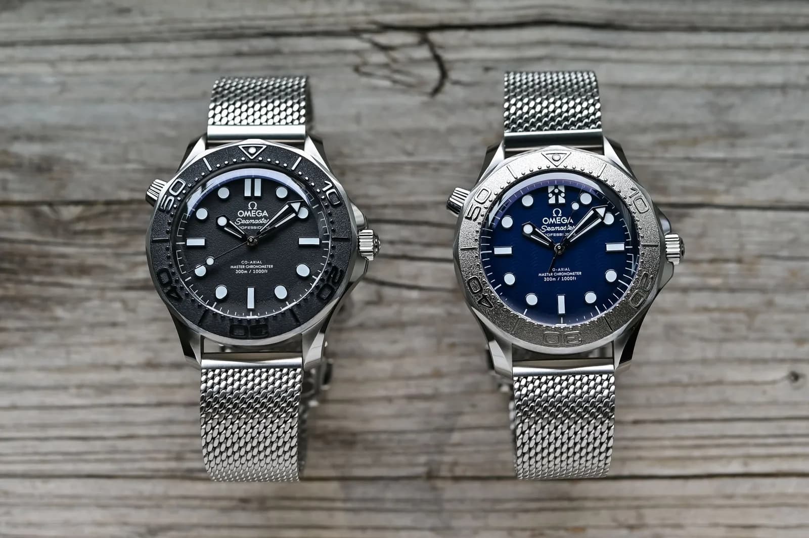 Zwei Omega Seamaster Diver 300M am Mesh-Band: links Spectre mit schwarzer Lünette, rechts James Bond mit Titanlünette und blauem Blatt