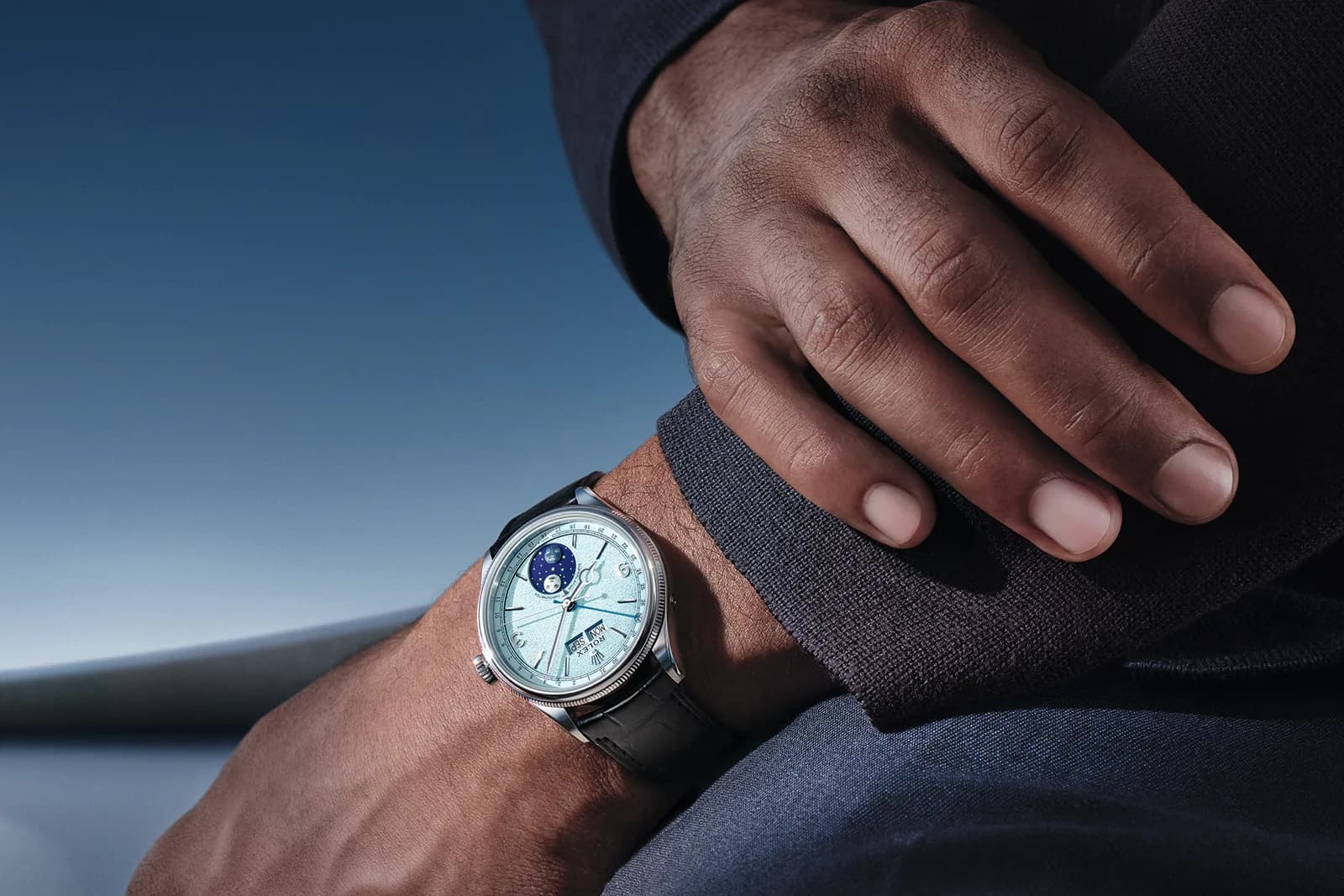Rolex Perpetual Padellone in Platin mit eisblauem Zifferblatt, Mondphase und schwarzem Lederband am Handgelenk